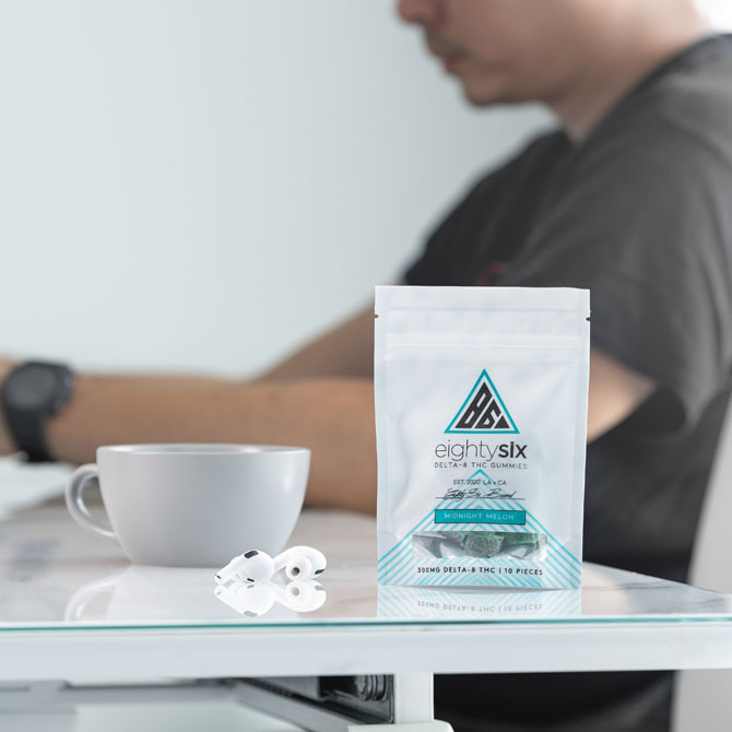 The Midnight Melon Delta-8 THC Gummies on a table with a man in the background.