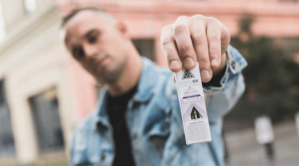 Man holding Eighty Six Purple Punch cartridge