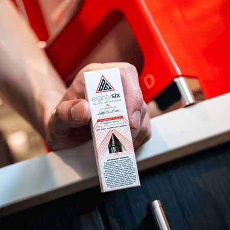 Person holding Strawberry Cough Delta-8 cartridge