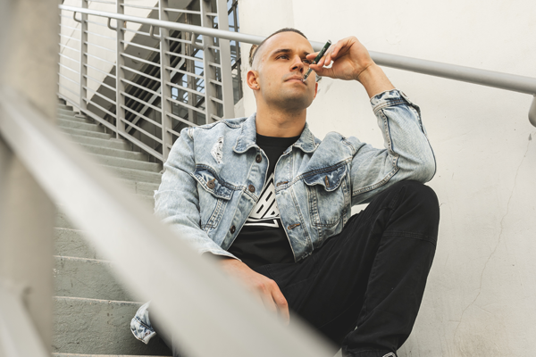 man sitting in a stair holding delta-8 thc vape 