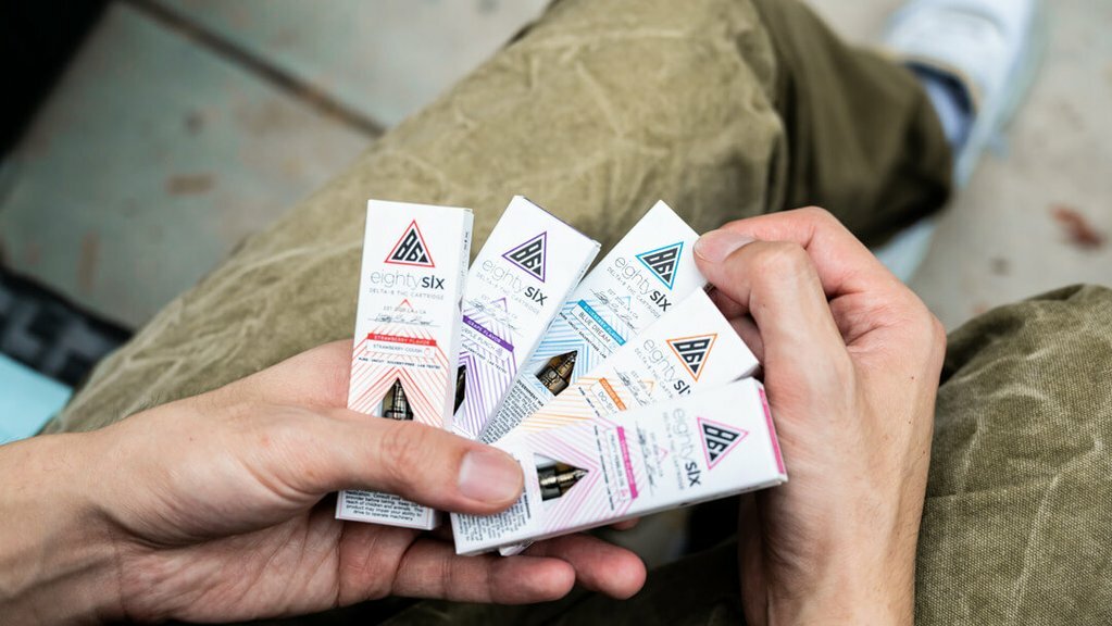 Person holding Eighty Six vape cartridge boxes